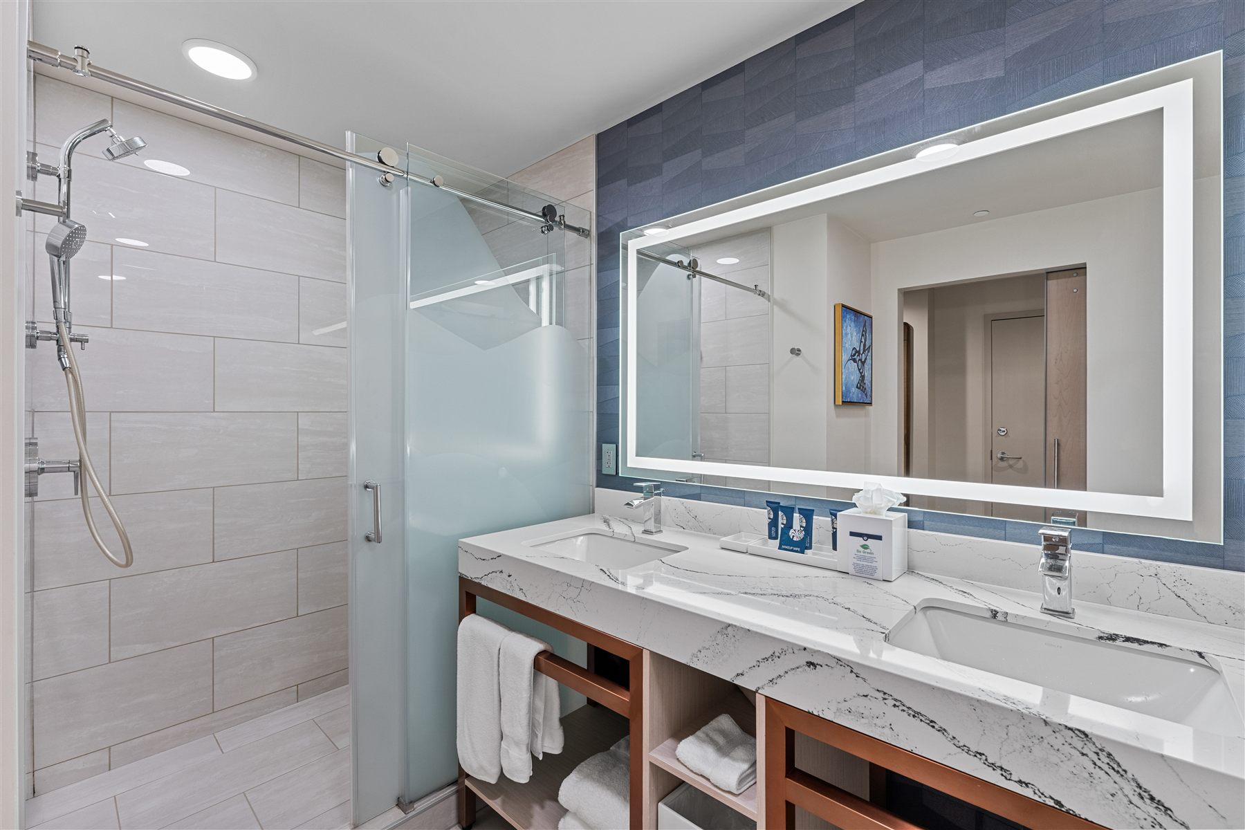 Hotel bathroom with marble counter and a lit vanity mirror