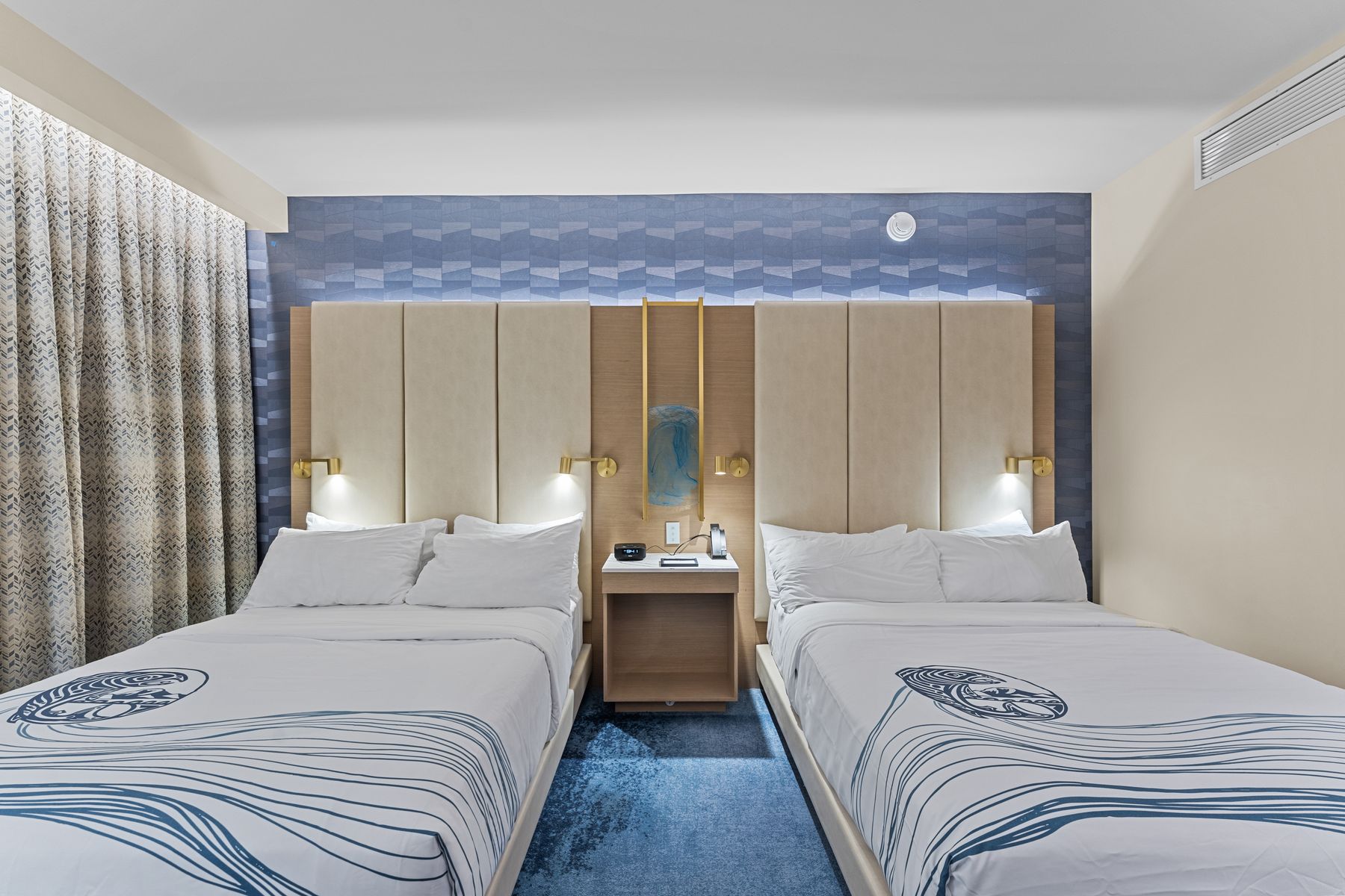 Hotel guest room shot straight on, two queen beds against a blue accent wall
