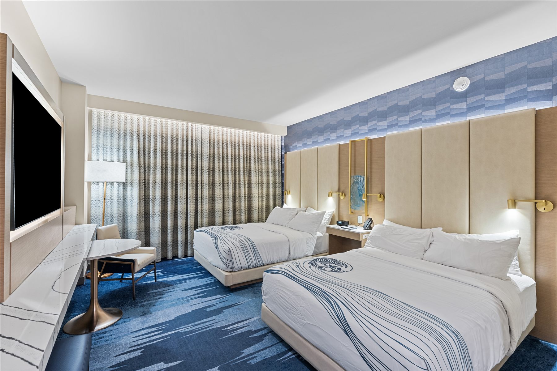 Hotel room with desk, seating and floor to ceiling curtains