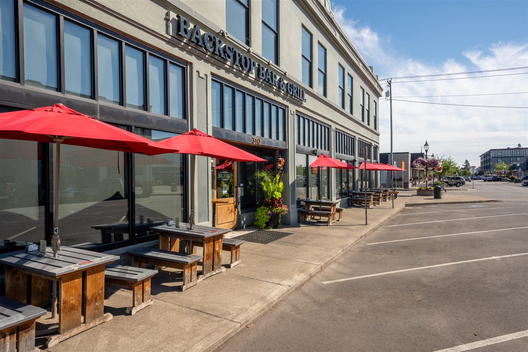 Bar and grill street frontage with red patio umbrellas and sidewalk seating