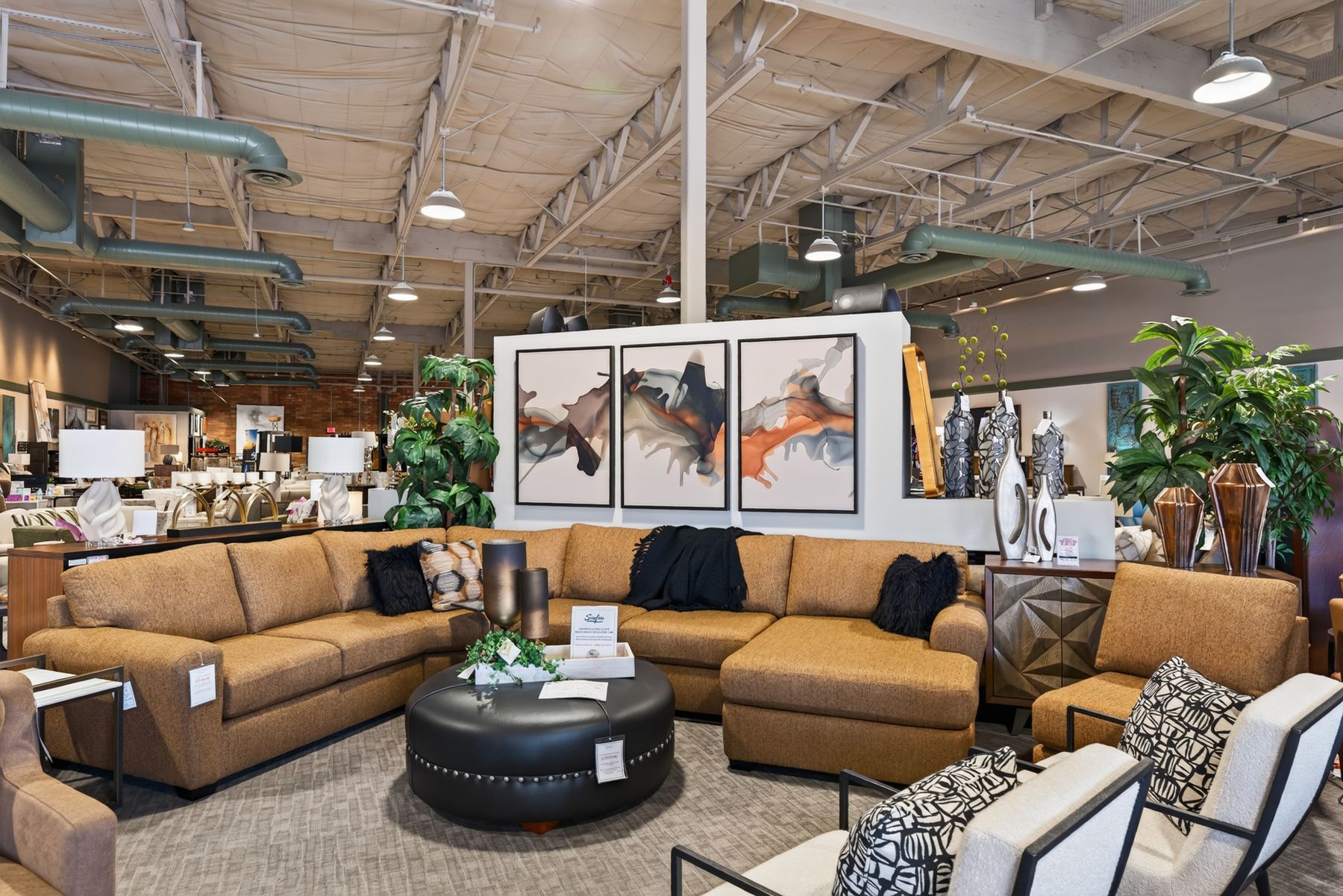 Sectional sofa staged beneath a three-panel abstract triptych in a furniture showroom