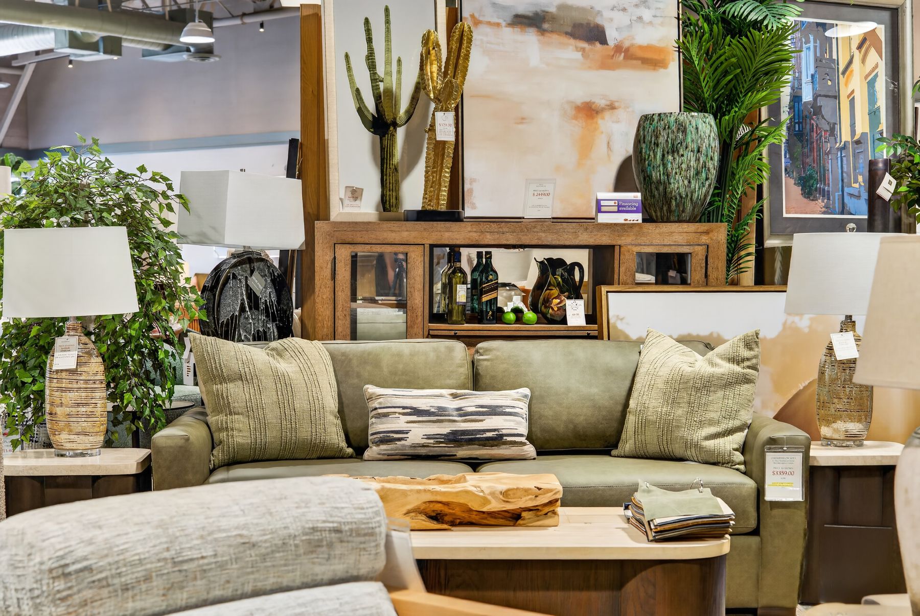 Green sofa styled with cushions and lamps in front of a console table in a Scottsdale furniture showroom