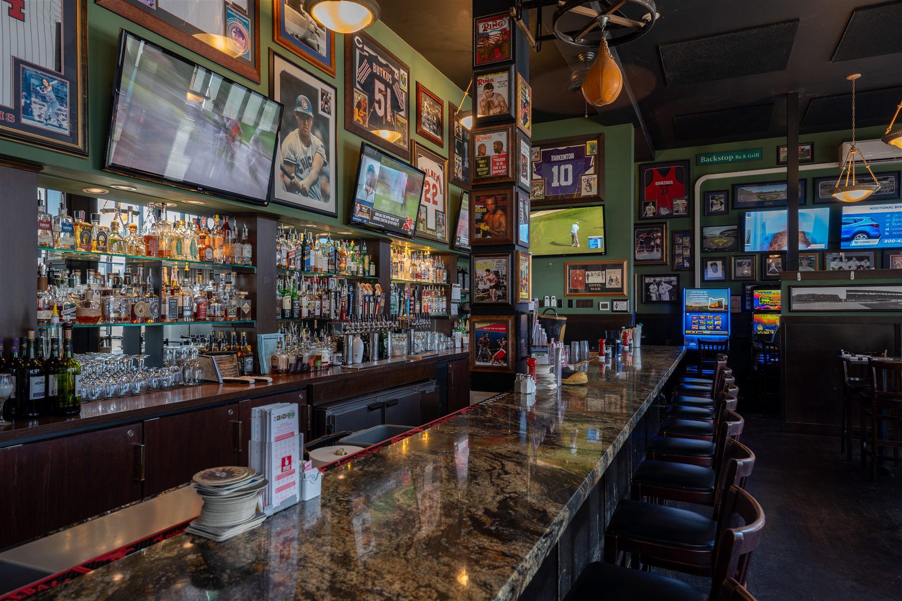 Sports bar interior with framed memorabilia covering a green wall