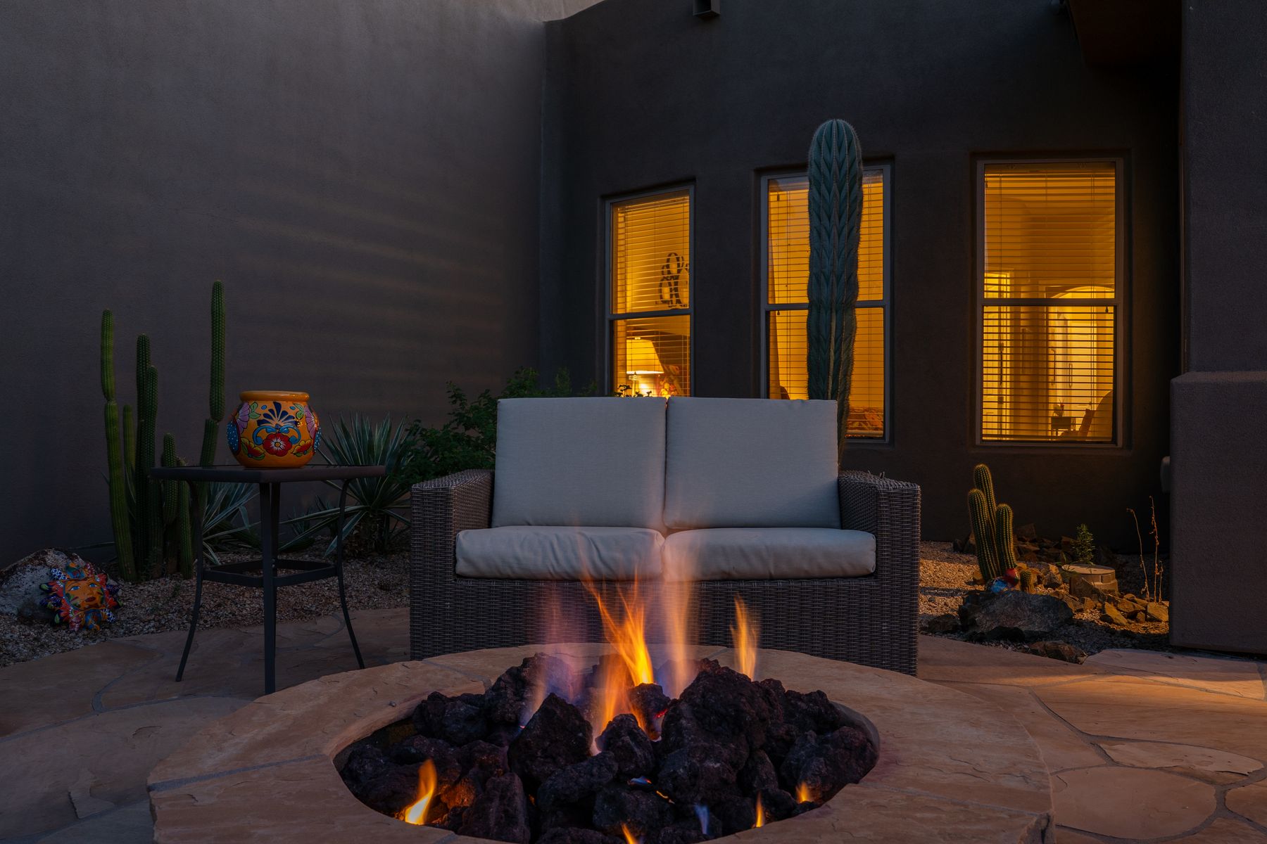 Blue hour patio with a lit fire pit and warm window light behind